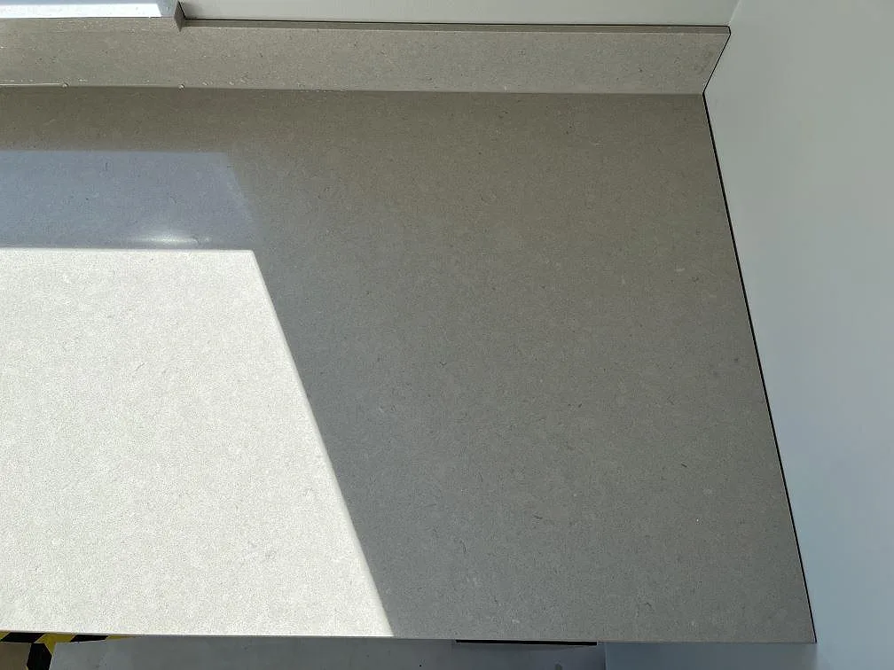 Hörnsektion av köksbänkskiva i Silestone Royal Reef med uppvikt stänkkant mot vit vägg i Bergkvara.
