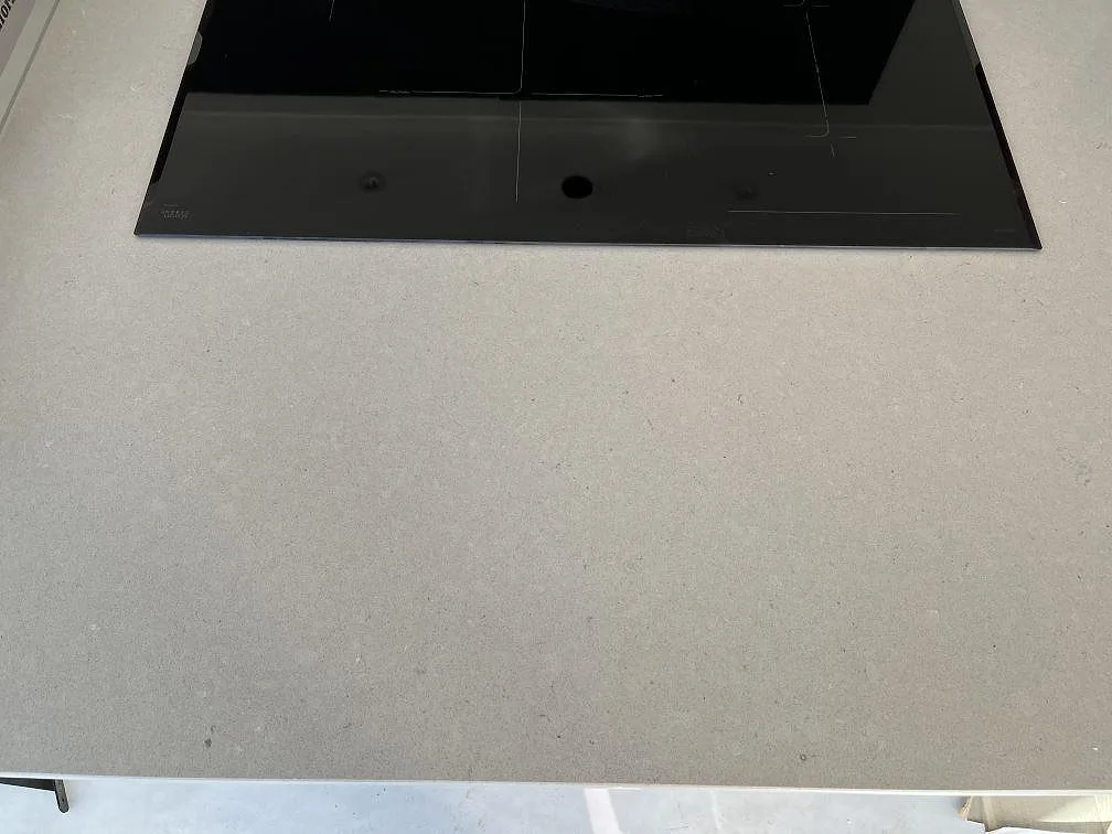 Närbild av polerad Silestone Royal Reef som köksbänkskiva med svart induktionshäll i Bergkvara.