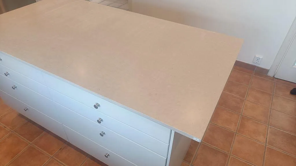 Stor köksö med bänkskiva i matt Silestone Royal Reef ovanpå vita köksskåp och terrakottafärgat golv i Bjärred.