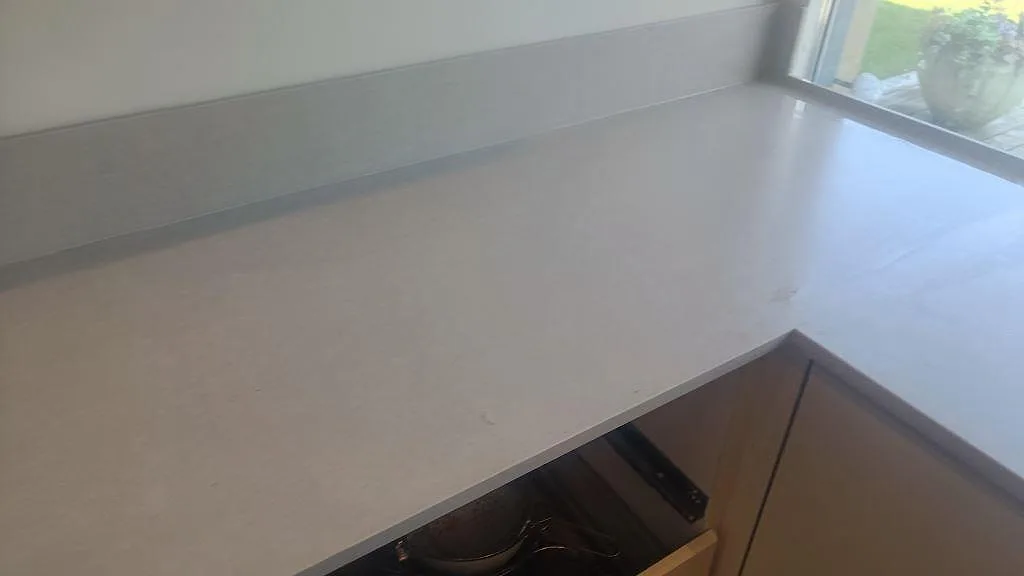 Hörn av köksbänkskiva i matt Silestone Royal Reef med låg stänkkant och fönsterljus i Bjärred.