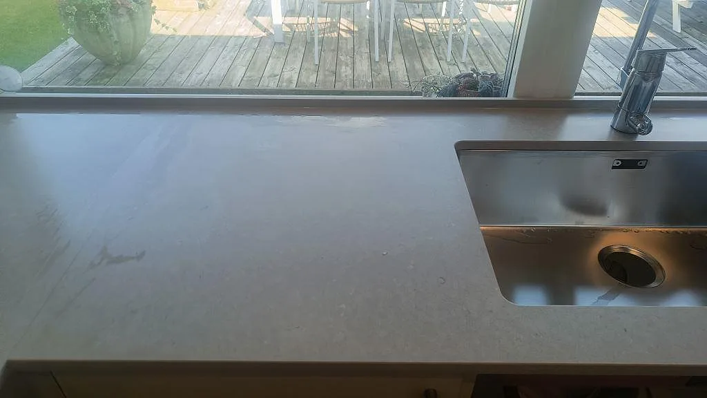 Bänkskiva i matt Silestone Royal Reef vid fönster med rostfri diskho och blandare i ett kök i Bjärred.