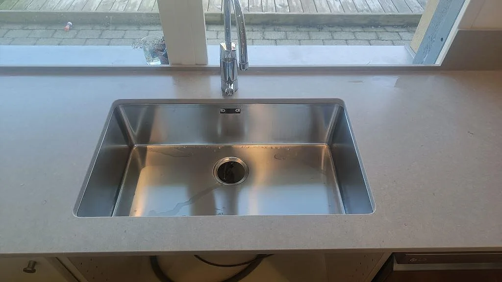 Underlimmad rostfri diskho i bänkskiva av matt Silestone Royal Reef med trädgårdsfönster i Bjärred.