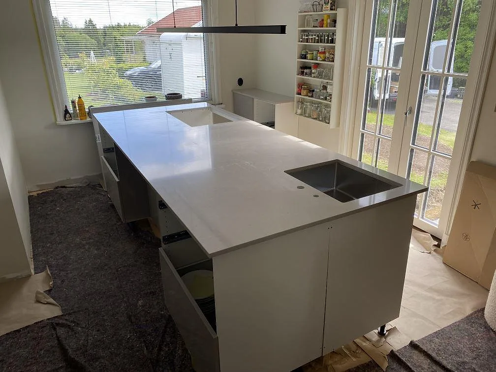 Polerad köksbänkskiva i Silestone Royal Reef komposit på en stor köksö med rostfri diskho och hällöppning i Borås.