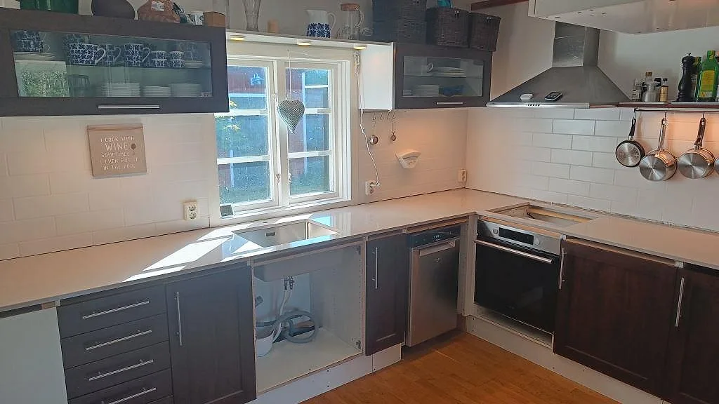 Polerad köksbänkskiva i Silestone Royal Reef, komposit, längs två väggar med rostfri diskho och hällöppning i Ekeby.