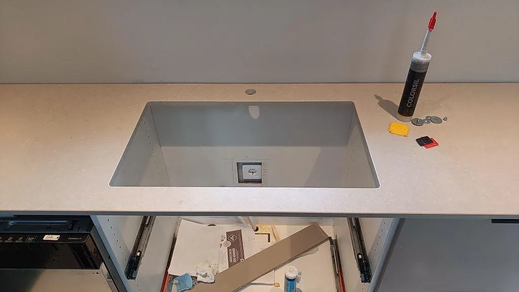 Underlimmad diskho med urtag och kranhål i en matt beige Silestone Royal Reef-bänkskiva i ett kök i Fagerfjäll.