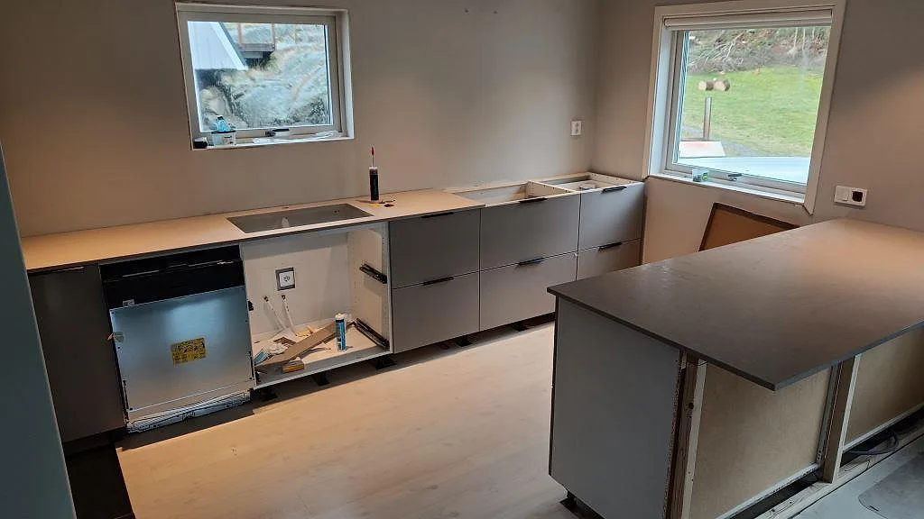 Köksbänkskiva i beige Silestone Royal Reef med matt Mocka-yta, monterad längs väggen och på en köksö i ett kök under montering i Fagerfjäll.