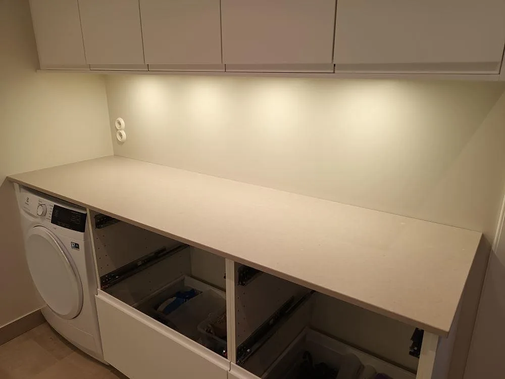 Köksbänkskiva i beige Silestone Royal Reef med Mocka-yta, monterad i en tvättstuga i Falun under installation med öppna stommar.