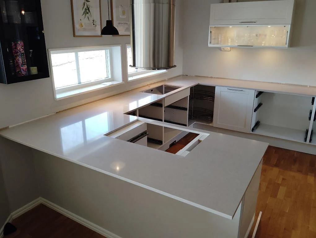 Köksbänkskiva i polerad Silestone Royal Reef, 20 mm kvartskomposit, monterad i ett U-format kök med halvö i Falun.