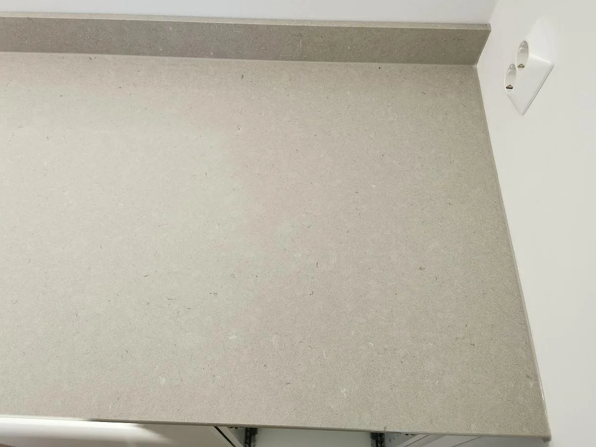 Ovanifrån av krämvit polerad Silestone Royal Reef köksbänkskiva med låg stänkkant och vägguttag i ett kök i Göteborg.