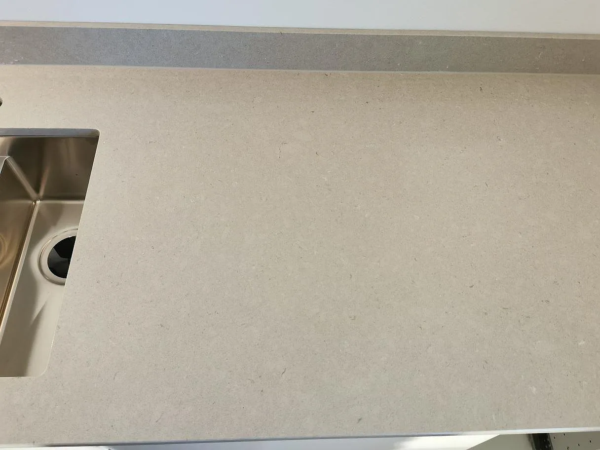Köksbänkskiva i krämvit Silestone Royal Reef, polerad, med underlimmad rostfri diskho och blandarehål i ett kök i Göteborg.