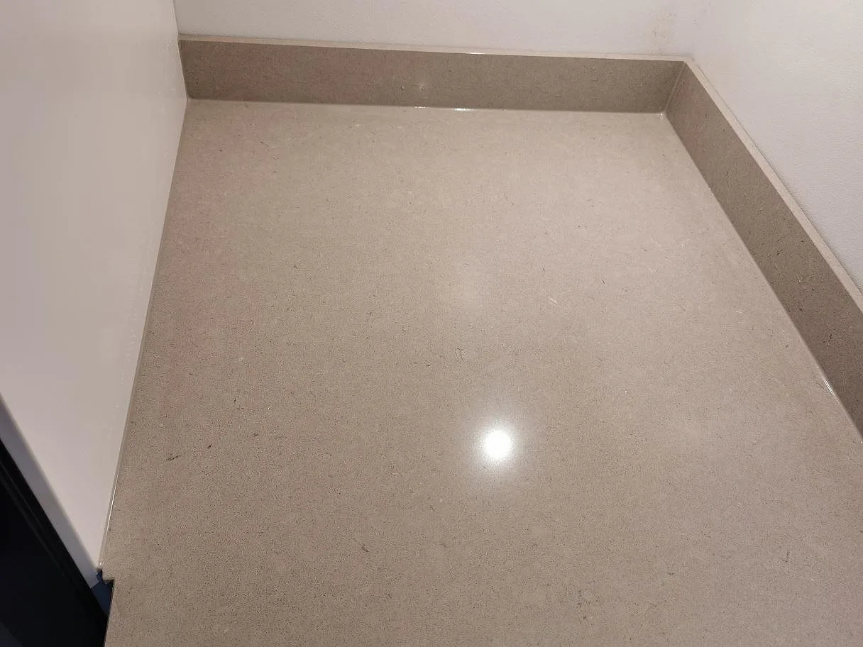 Hörn av polerad Silestone Royal Reef köksbänkskiva med uppvikt stänkkant mot väggen i ett kök i Göteborg.