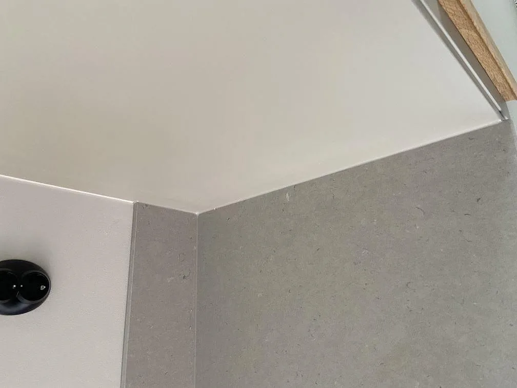 Hörndetalj där en matt Silestone Royal Reef-bänkskiva möter en uppvikt stänkkant mot vit vägg i ett kök i Göteborg.