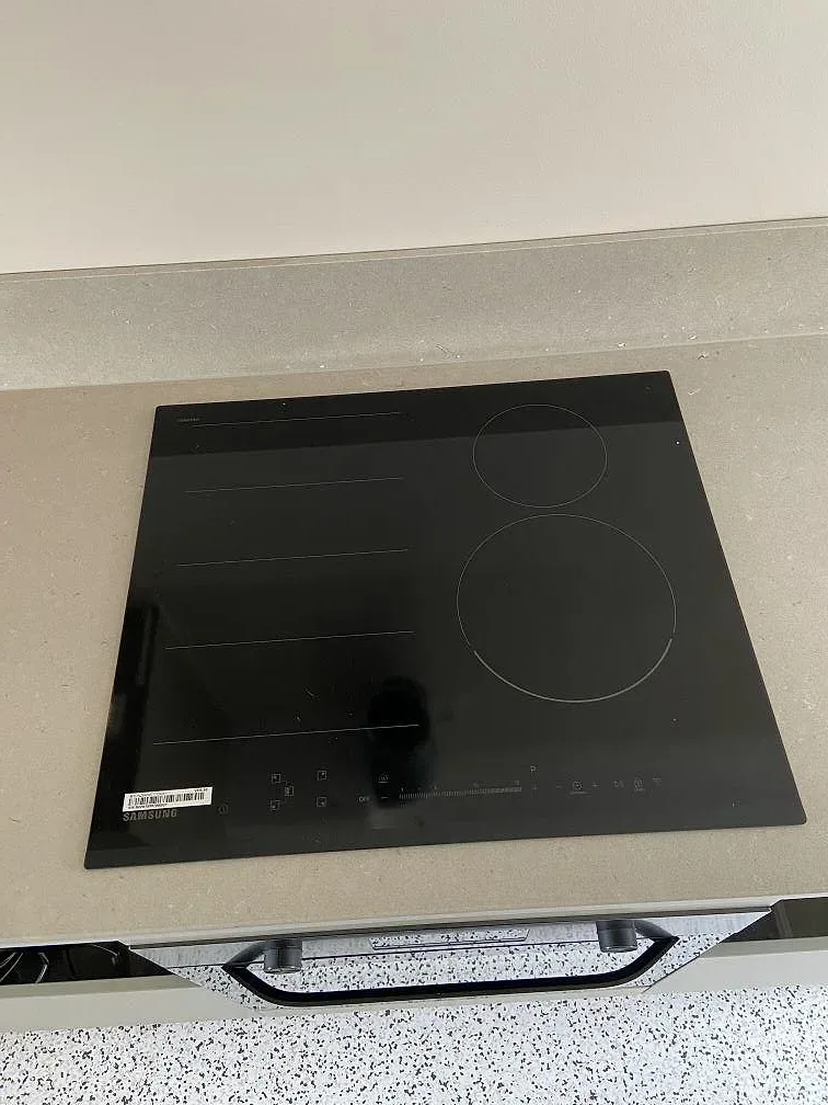 Infälld induktionshäll i svart glas i en matt gråbeige Silestone Royal Reef-bänkskiva i ett kök i Göteborg.