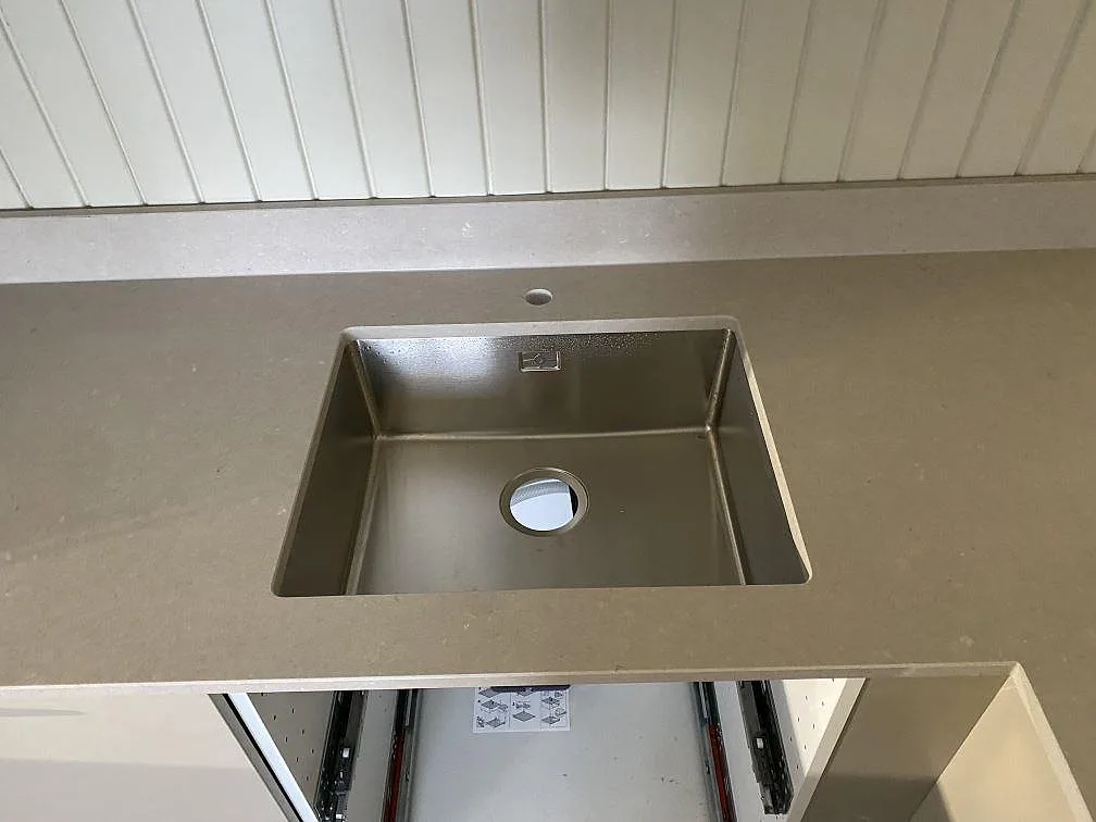 Närbild på underlimmad rostfri diskho i köksbänkskiva av polerad Silestone Royal Reef med uppvikt stänkkant i Göteborg.