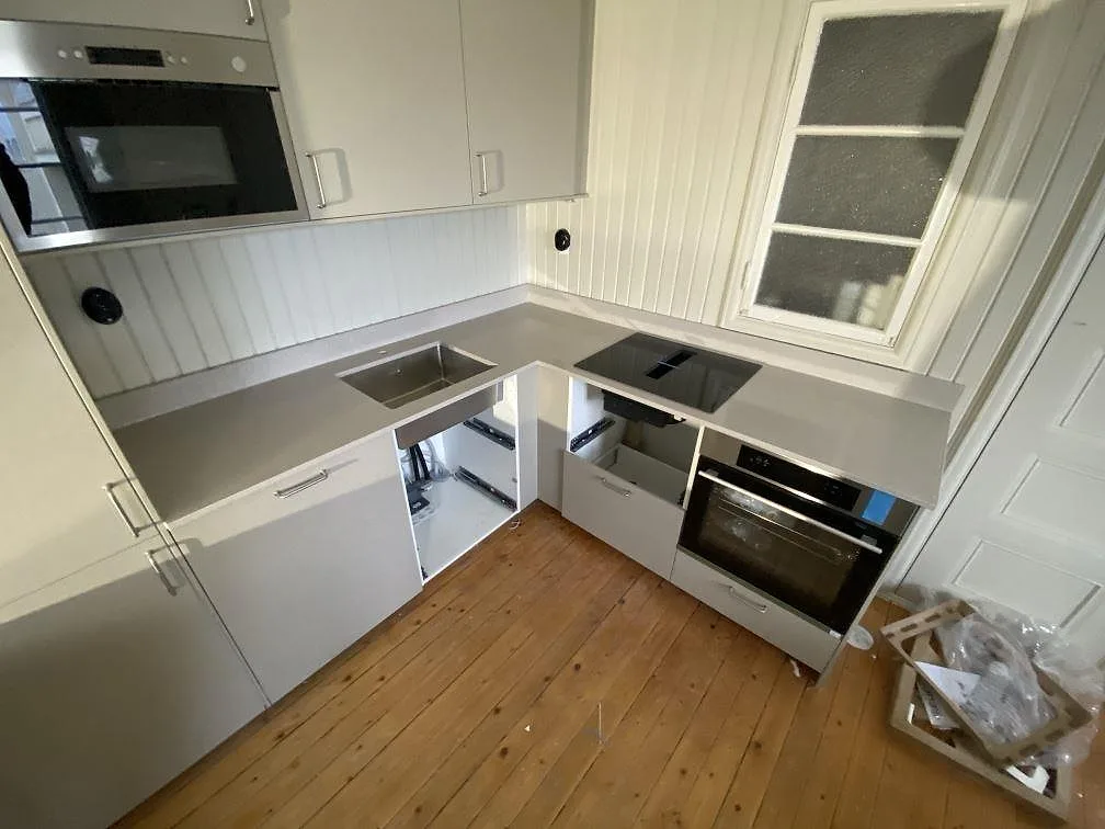Köksbänkskiva i beige Silestone Royal Reef, polerad, i ett L-format kök med underlimmad komposithoar och infälld induktionshäll i Göteborg.