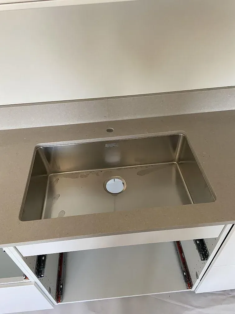Underlimmad rostfri diskho i en köksö av beige Silestone Royal Reef kvartskomposit i ett kök i Hässleholm.