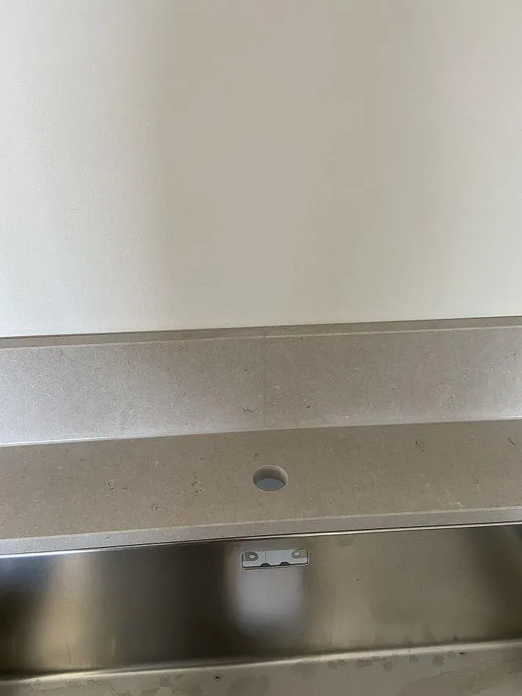 Separat borrat blandarhål i bänkskiva av matt Silestone Royal Reef i ett kök i Hässleholm.