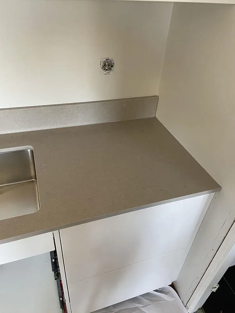 Köksö med kraftig nedfälld sida i beige Silestone Royal Reef kvartskomposit i ett kök i Hässleholm.