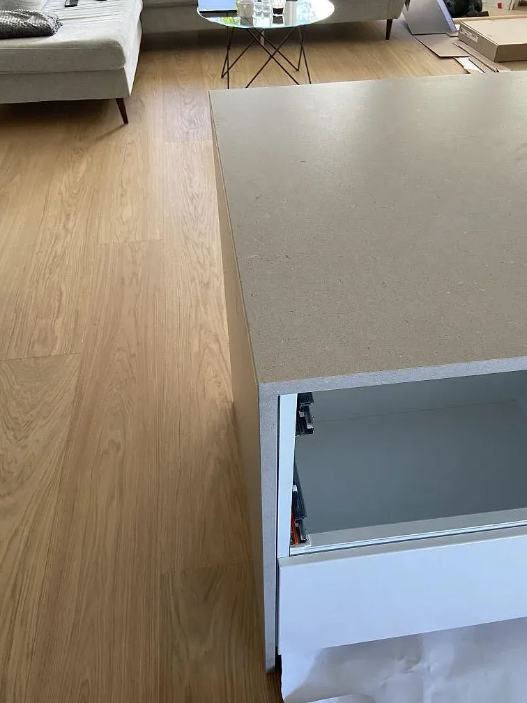 Bänkskiva i sandbeige Silestone Royal Reef mot vit köksstomme och trägolv i ett kök i Hässleholm.