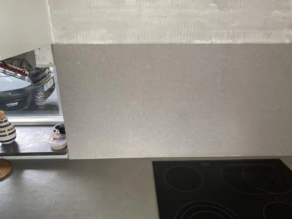 Stänkskydd och bänkskiva i matt Silestone Royal Reef ovanför svart induktionshäll i Höllviken.