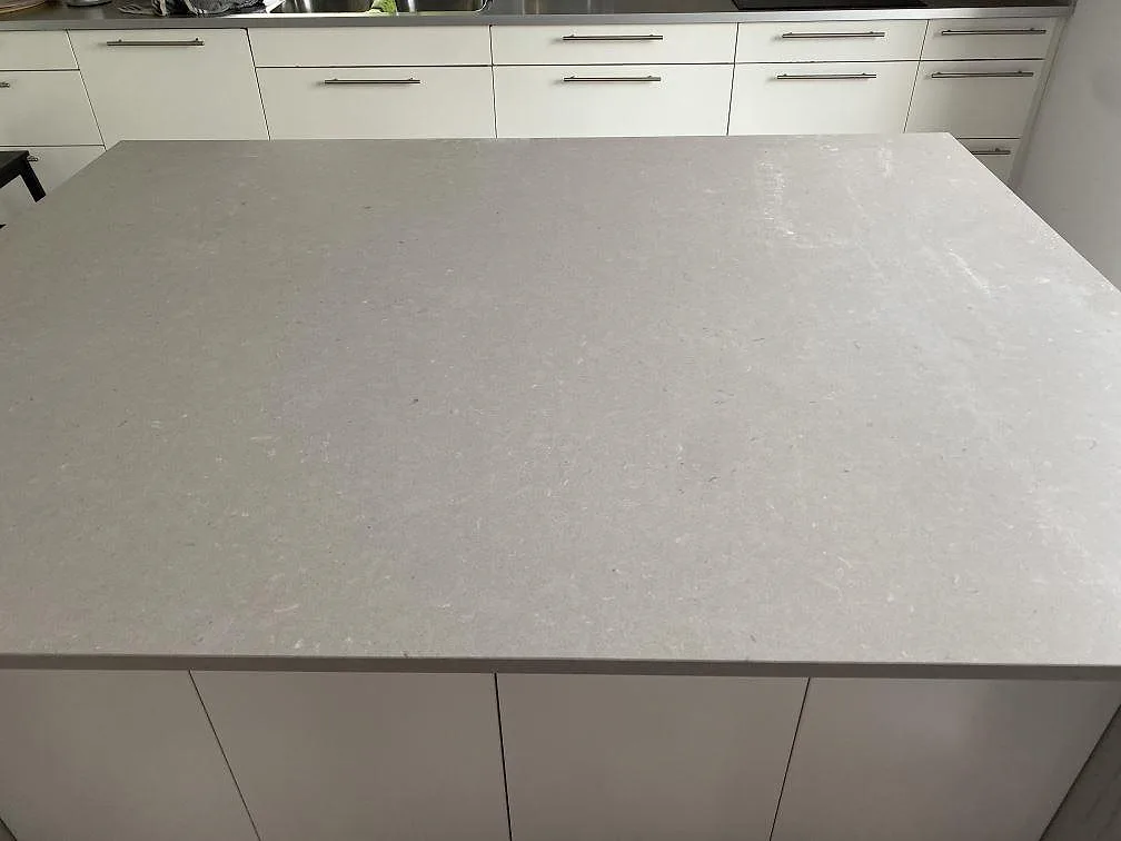 Närbild på stor köksö med matt Silestone Royal Reef som kompositskiva, vita luckor och kök i Höllviken.