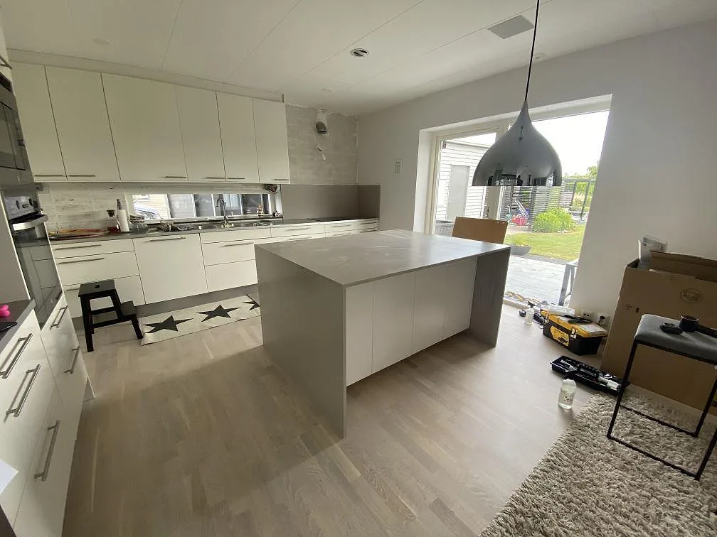 Köksbänkskiva och stor köksö i matt Silestone Royal Reef, ljus komposit, i ett vitt kök i Höllviken.