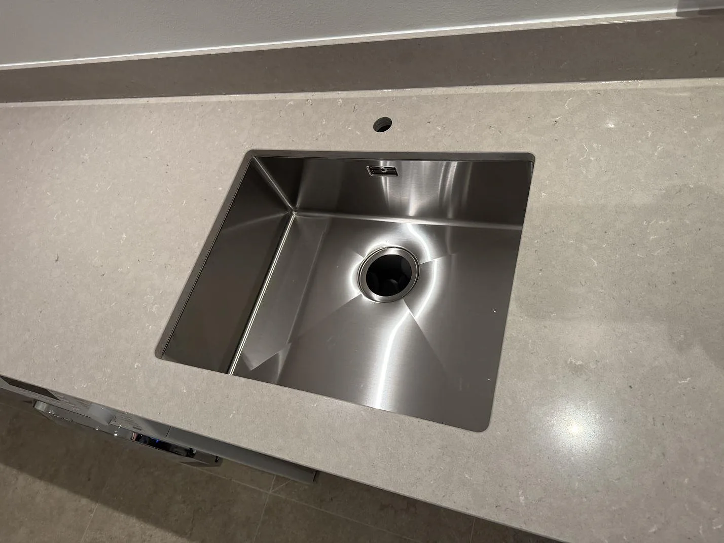 Närbild av rostfri diskho i en polerad Silestone Royal Reef bänkskiva med ljus komposityta i Höllviken.