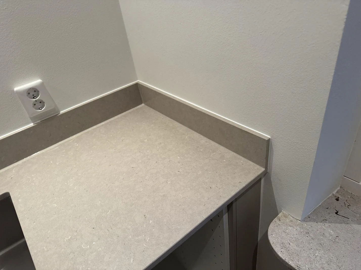 Hörn av bänkskiva i polerad Silestone Royal Reef med uppvikt stänkkant och ljus komposityta i Höllviken.