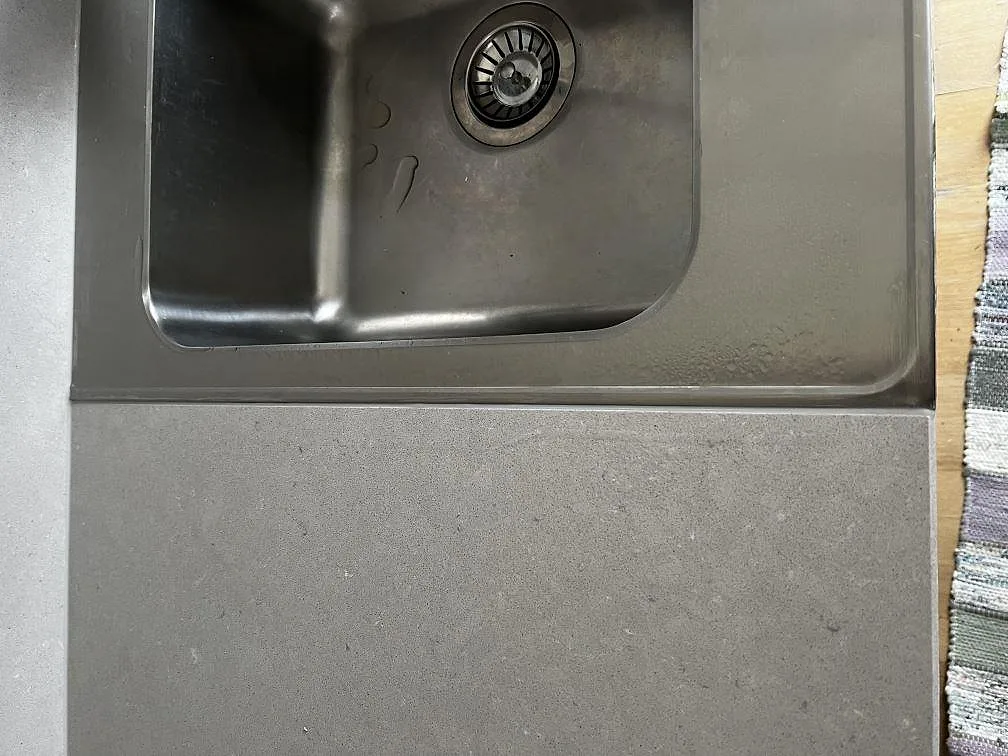 Underlimmad rostfri diskho i polerad köksbänkskiva av vit Silestone Royal Reef i ett kök i Huskvarna.