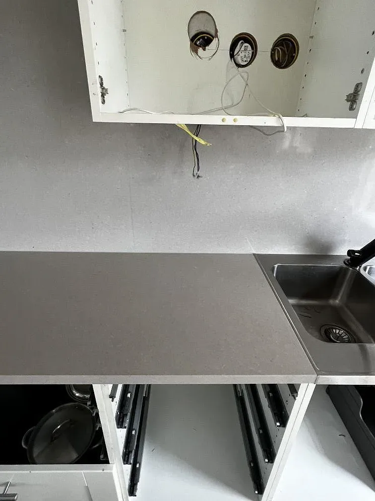 Underlimmad rostfri diskho och öppna lådstommar intill polerad bänkskiva i Silestone Royal Reef i ett kök i Huskvarna.