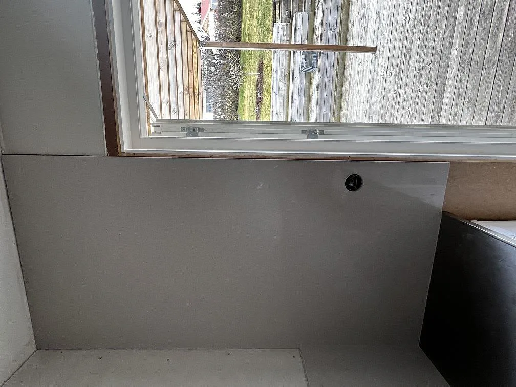 Köksbänkskiva i vit Silestone Royal Reef med grå revådring, polerad, monterad under ett fönster med urtag för köksblandare i ett kök i Huskvarna.