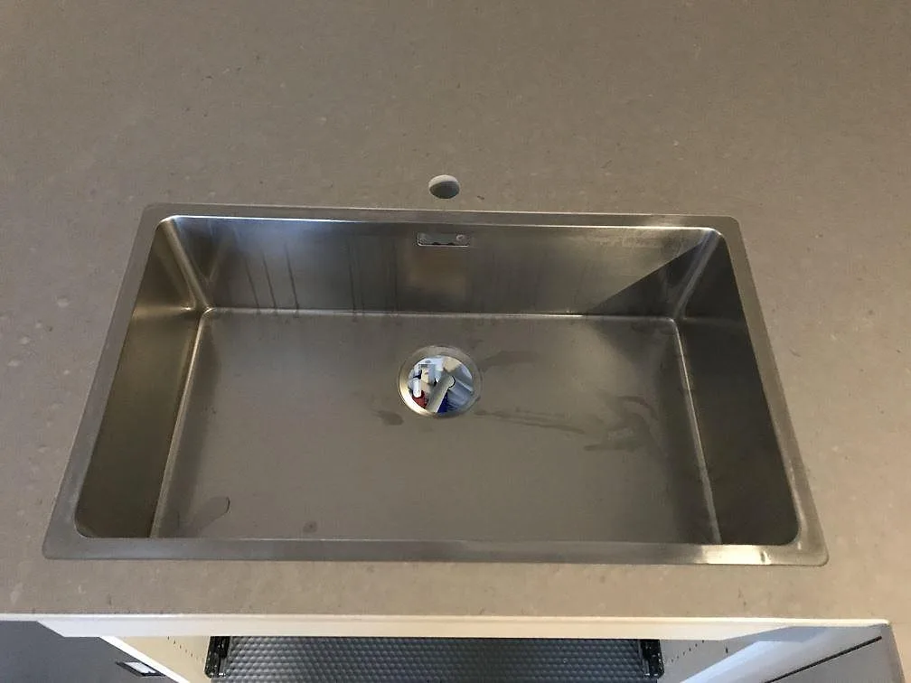 Närbild på stor rostfri underlimmad diskho i polerad Silestone Royal Reef bänkskiva i ett kök i Jönköping.