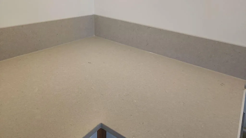 Närbild på den matta greige ytan och den uppvikta stänkkanten i Silestone Royal Reef i ett kök i Kalmar.