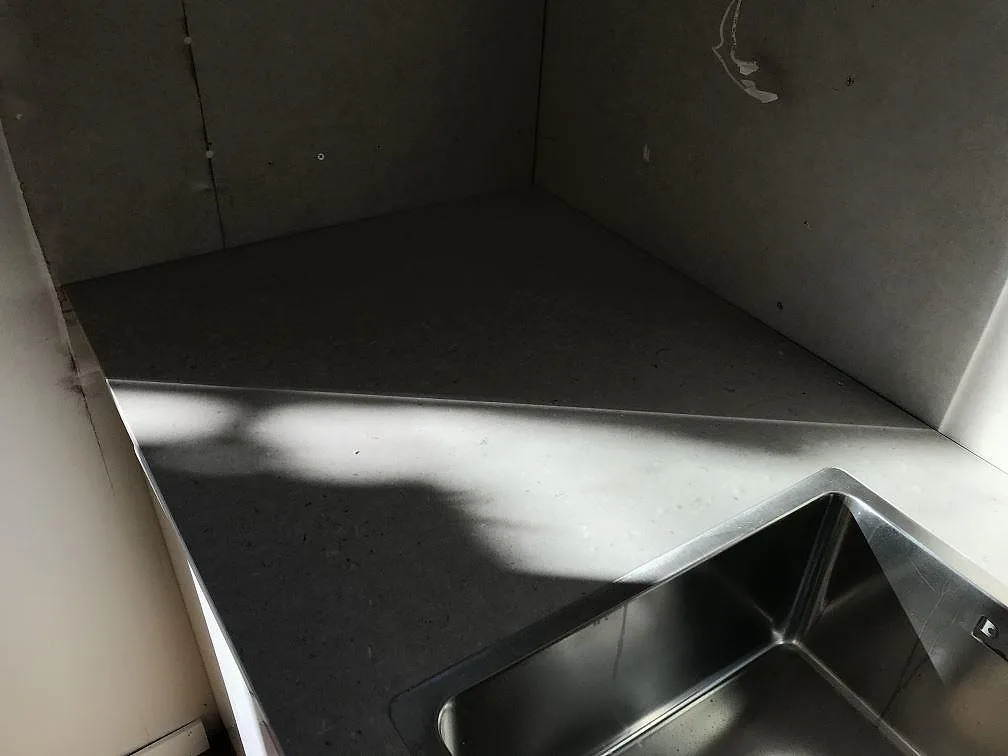 Underlimmad rostfri diskho i hörnet på en köksbänk i Silestone Royal Reef, polerad beige komposit i Karlskrona.