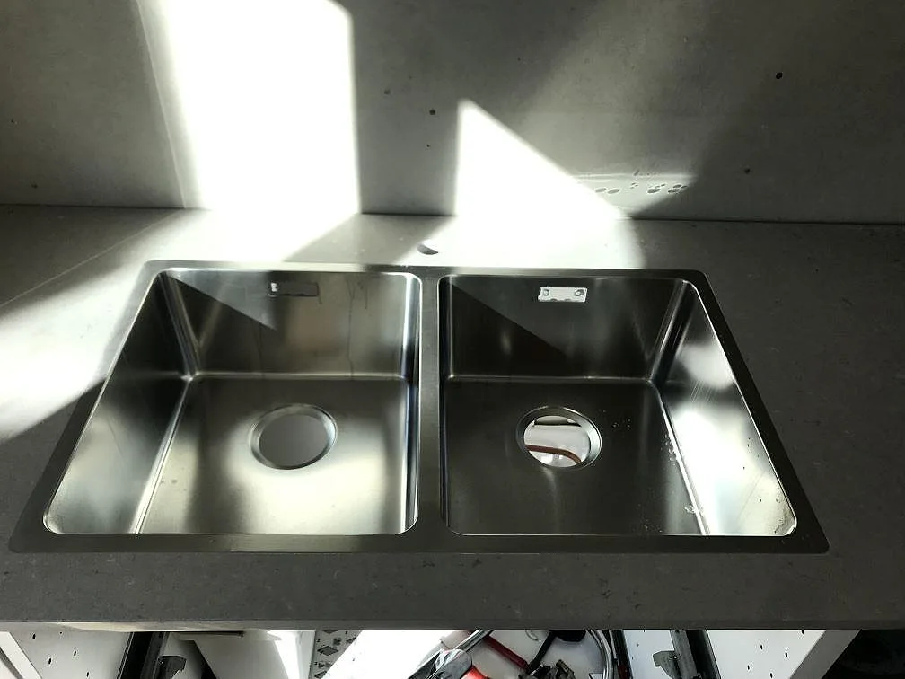 Två underlimmade rostfria diskhoar i en bänkskiva av beige Silestone Royal Reef i ett kök i Karlskrona.