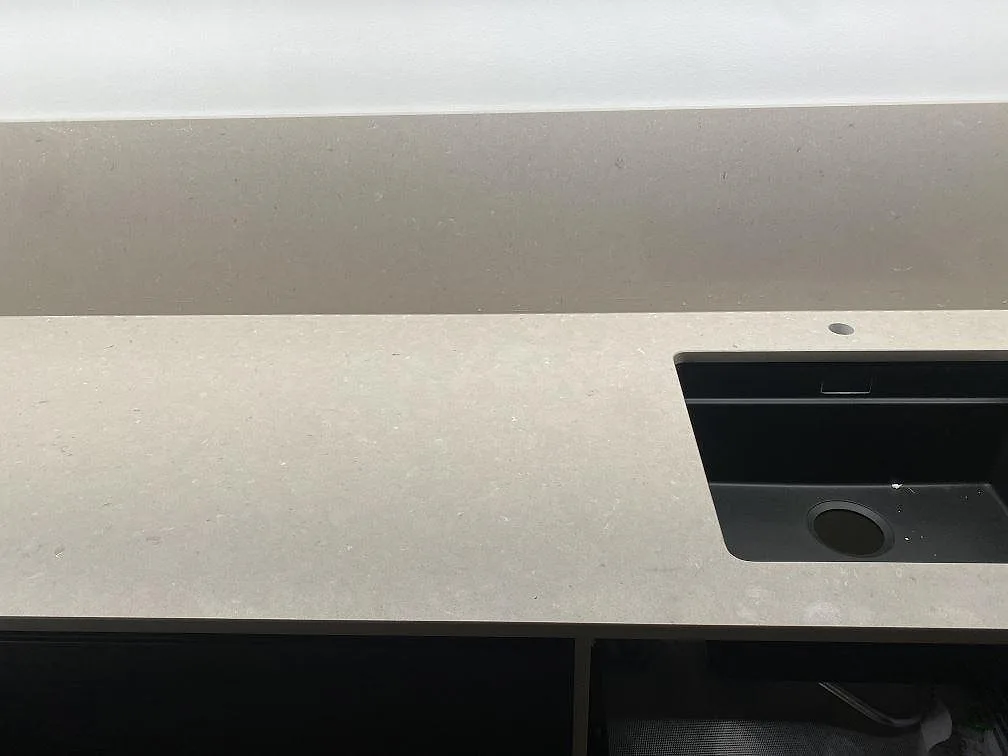 Köksbänkskiva i beige Silestone Royal Reef, matt Mocka, med svart underlimmad diskho och uppvikt stänkskydd i ett kök i Klågerup.