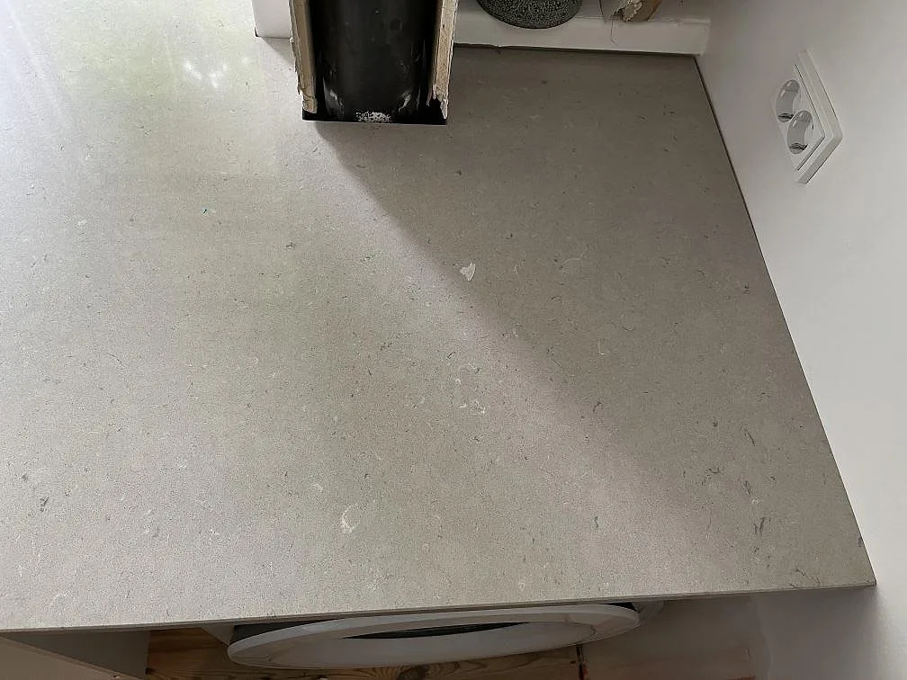 Sandbeige Silestone Royal Reef köksbänkskiva sedd uppifrån i ett kök under montering i København N., med vägguttag och tvättmaskin under bänken.