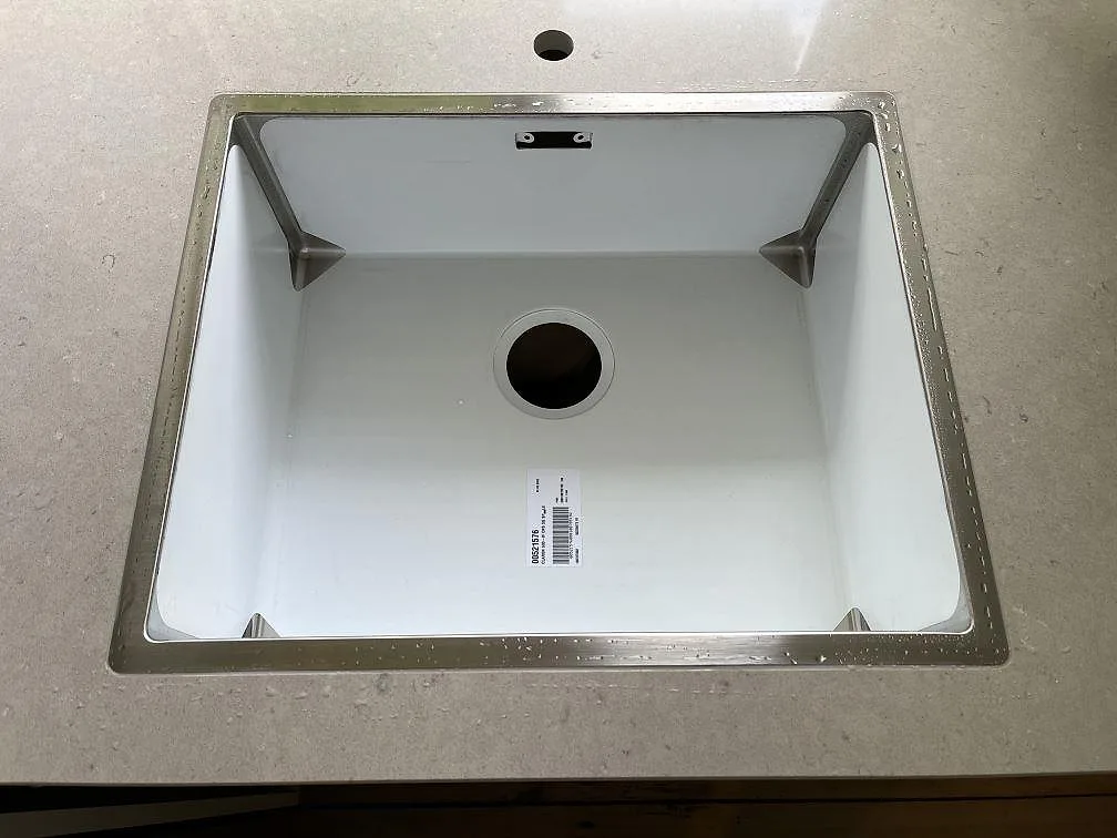 Underlimmad diskho med rostfri kant nedfälld i sandbeige Silestone Royal Reef köksbänkskiva, sedd uppifrån, i København N.