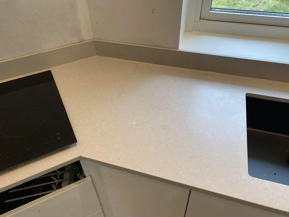 Hörnsektion av köksbänkskiva i Silestone Royal Reef med infälld induktionshäll och fönsterbänk i samma sten i Kristianstad.