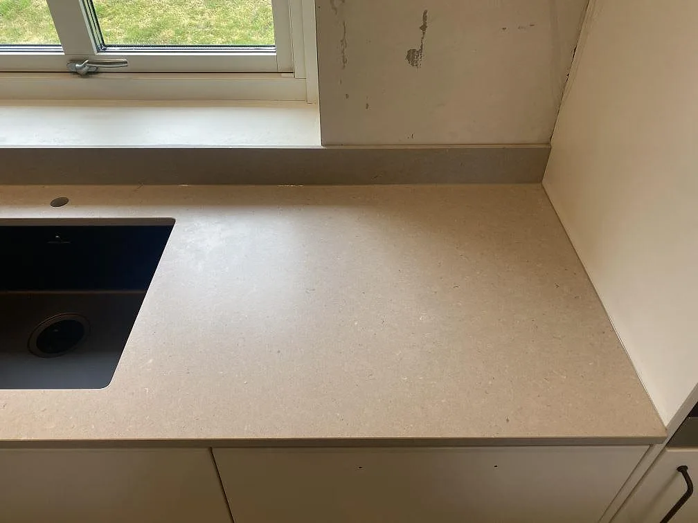 Köksbänkskiva i Silestone Royal Reef med underlimmad svart kompositdiskho och matchande fönsterbänk i ett kök i Kristianstad.