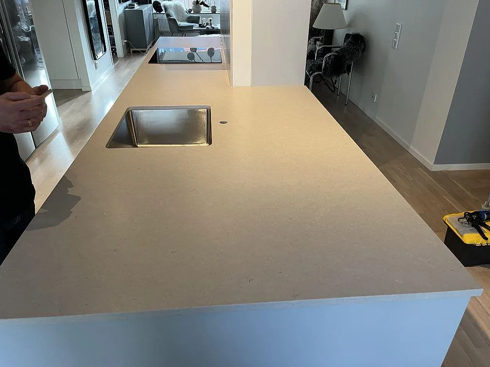 Köksbänkskiva i beige Silestone Royal Reef komposit med rostfri diskho och svart induktionshäll i ett öppet kök i Limhamn.