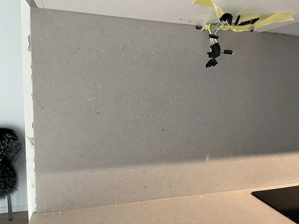 Stänkskydd och bänkskiva i beige Silestone Royal Reef komposit bakom induktionshäll i kök i Limhamn.