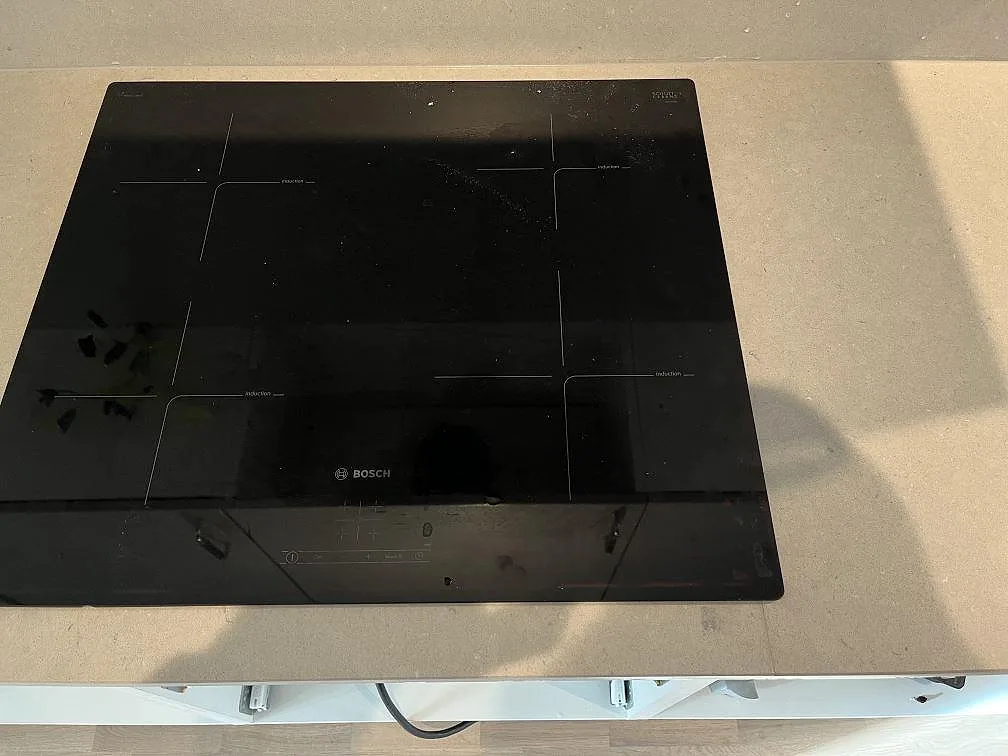 Svart Bosch induktionshäll monterad i beige Silestone Royal Reef kompositbänkskiva i Limhamn.