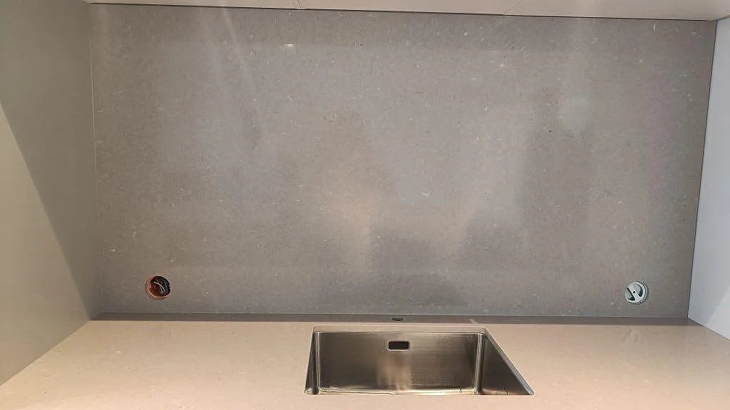 Köksbänkskiva i polerad Silestone Royal Reef med matchande väggbeklädnad och synlig rostfri diskho i Limhamn.