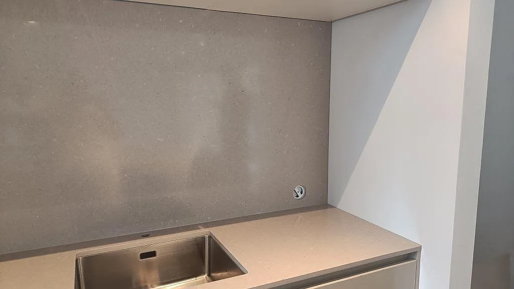 Höger sida av köksbänkskiva i polerad Silestone Royal Reef med grå väggbeklädnad och ljus nisch i Limhamn.