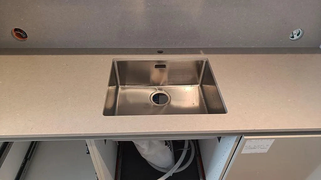 Detaljbild av polerad Silestone Royal Reef runt en synlig rostfri diskho och väggbeklädnad i köket i Limhamn.