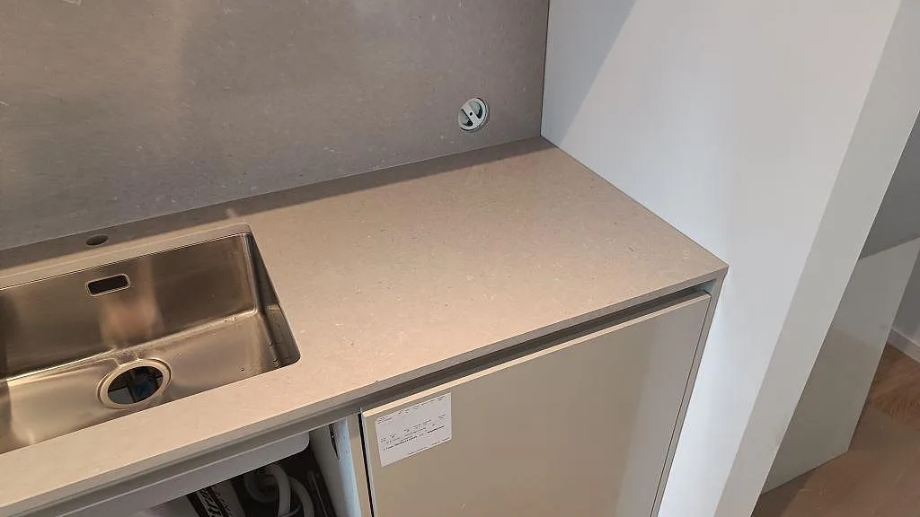 Höger bänkyta i polerad Silestone Royal Reef med varm gråbeige ton, väggbeklädnad och monteringsstommar i Limhamn.