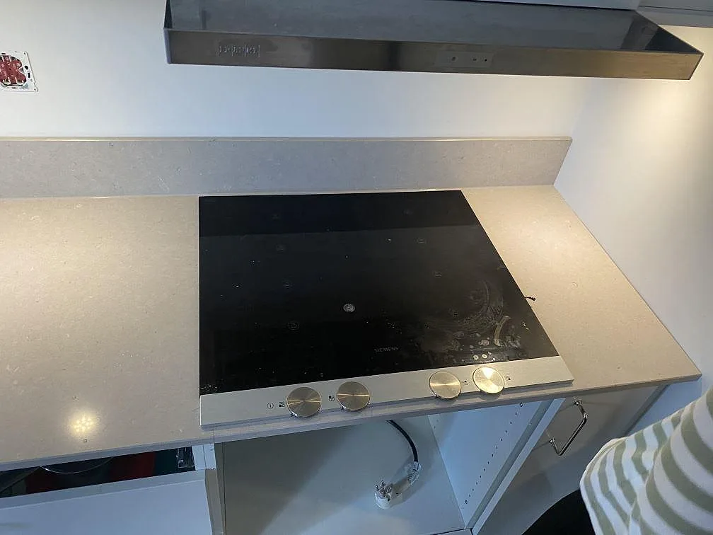 Köksbänkskiva i Silestone Royal Reef med svart häll och matchande stänkskydd under fläkt i Lund.