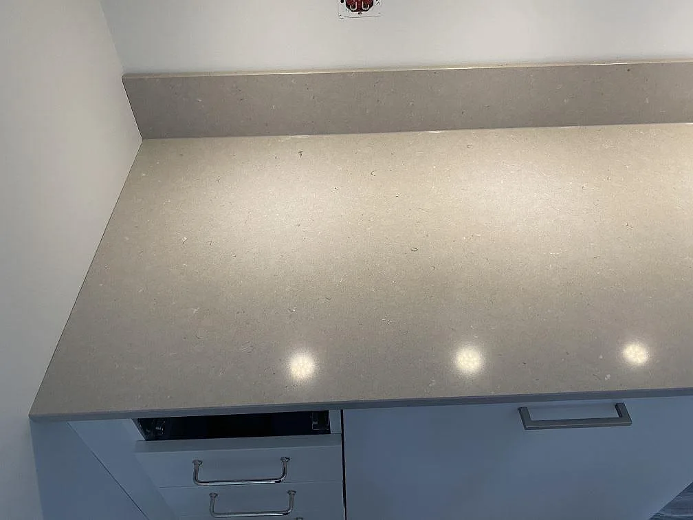 Sidobänk i polerad Silestone Royal Reef med uppvikt stänkskydd på vita köksskåp i Lund.