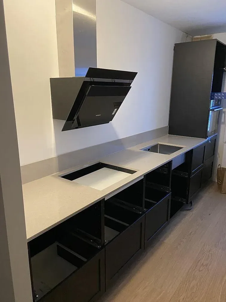 Köksbänkskiva i beige Silestone Royal Reef, kvartskomposit, med fristående köksö och induktionshäll i ett kök under montering i Malmö.